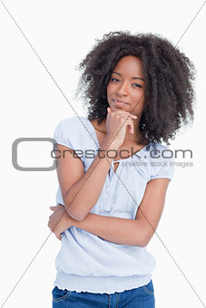 Young woman standing up with hand on chin and arms crossed