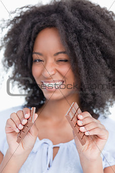Young woman breaking a delicious chocolate bar into two parts