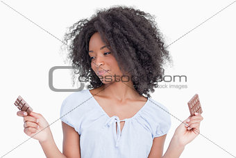 Young woman looking at one of her two pieces of chocolate
