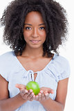 Young curly woman holding a green apple in her hands