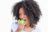 Young woman looking on the side while eating a green apple