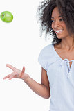 Young woman throwing a green apple in the air