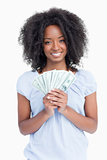 Young smiling woman with curly hair holding a fan of dollar note
