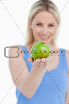 Delicious green apple held by a smiling blonde woman