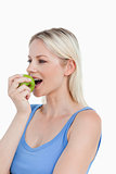 Blonde woman looking to the side while eating a green apple