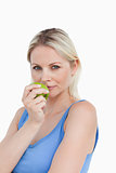 Blonde woman holding a green apple close to her mouth