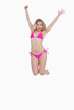 Dynamic blonde woman energetically jumping while wearing swimsui