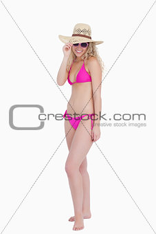 Young woman standing upright while holding her hat brim
