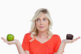 Woman hesitating between a chocolate muffin and a green apple