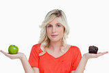 Young woman looking at the camera while holding a muffin and a g