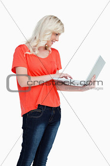 Woman standing upright while using the touchpad of her laptop