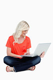 Young blonde woman sitting cross-legged with her laptop on her l