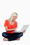 Fair-haired woman waving her right hand in front of her laptop s