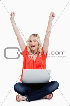 Attractive woman sitting cross-legged while raising her arms abo