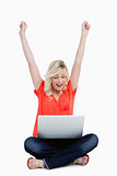 Young woman raising her arms in success in front of her laptop