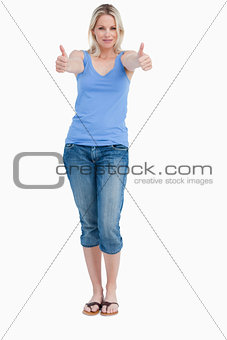 Blonde woman standing upright while placing her thumbs up
