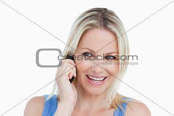 Smiling blonde woman looking on the side while on the phone