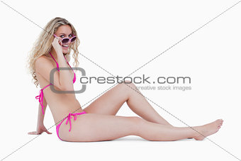 Attractive teenager sitting down while looking over her sunglass