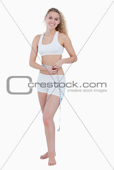 Smiling teenager using a measuring tape for her waist