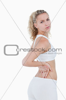 Young serious woman showing a pain in the back