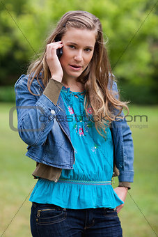 Teenage girl using her mobile phone while looking at the camera