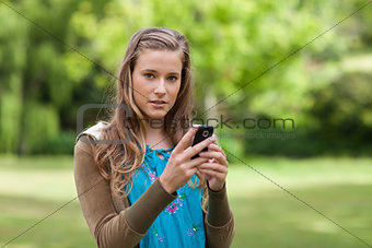 Teenage girl sending a text while looking at the camera
