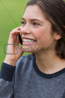 Young smiling girl calling with her cellphone while standing up