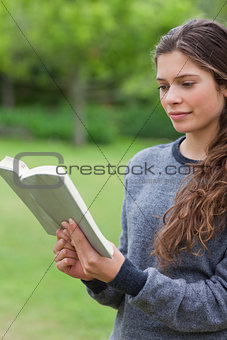 Young relaxed girl reading a book in a park