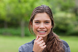 Smiling girl placing her hand on her chin while standing upright