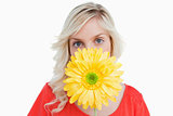 Fair-haired woman hiding her face behind a yellow flower