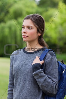 Thoughtful young girl standing in the countryside while carrying