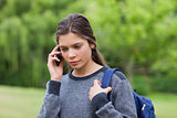Thoughtful young girl using her mobile phone while carrying her 