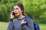 Young calm girl talking on the phone while looking towards the s