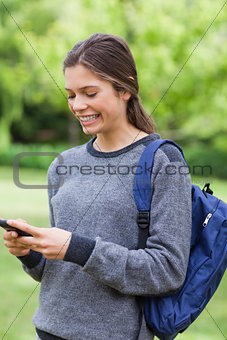 Smiling young girl sending a text with her mobile phone