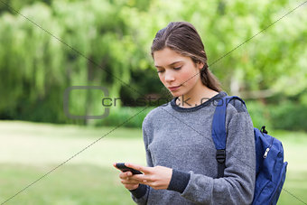 Young calm girl using her mobile phone to send a text