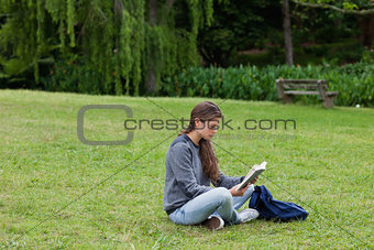 Young girl sitting cross-legged while reading a book