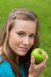 Attractive young girl holding a delicious green apple while stan