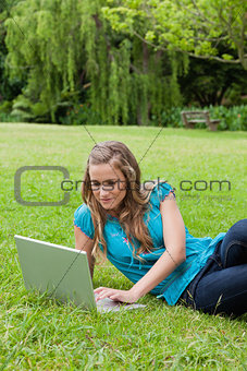 Young relaxed girl lying on the side while working on her laptop