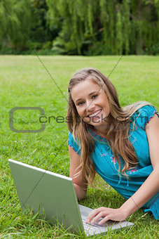 Young girl looking at the camera while using her laptop and smil