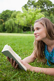 Thoughtful young woman holding a book while looking away