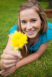 Smiling young woman holding a yellow flower while looking at the
