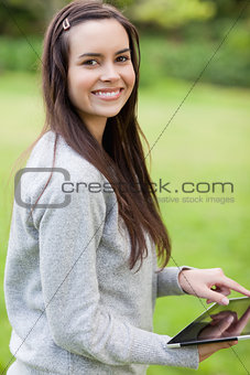 Young smiling woman using her tablet pc while looking at the cam