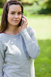 Young serious woman calling with her cellphone while standing in