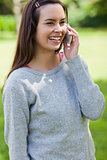 Young girl laughing while talking on the phone in a park