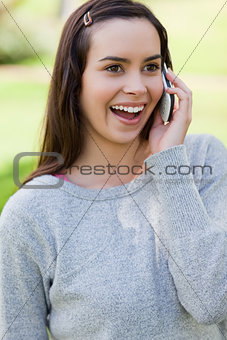 Surprised young woman talking on the phone while standing in a p