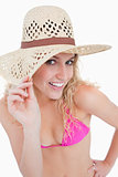 Young blonde woman looking at the camera while holding her hat b