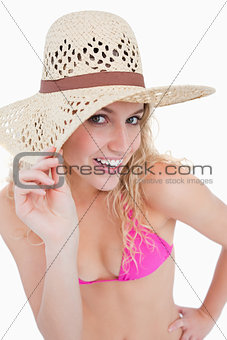 Young blonde woman looking at the camera while holding her hat b
