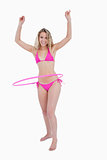 Smiling teenager playing hula-hoop with her arms raised