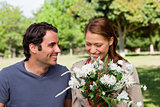 Woman happily looking into a bunch flowers as she is being watch