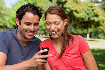 Two friends smiling as they are looking at something on a mobile